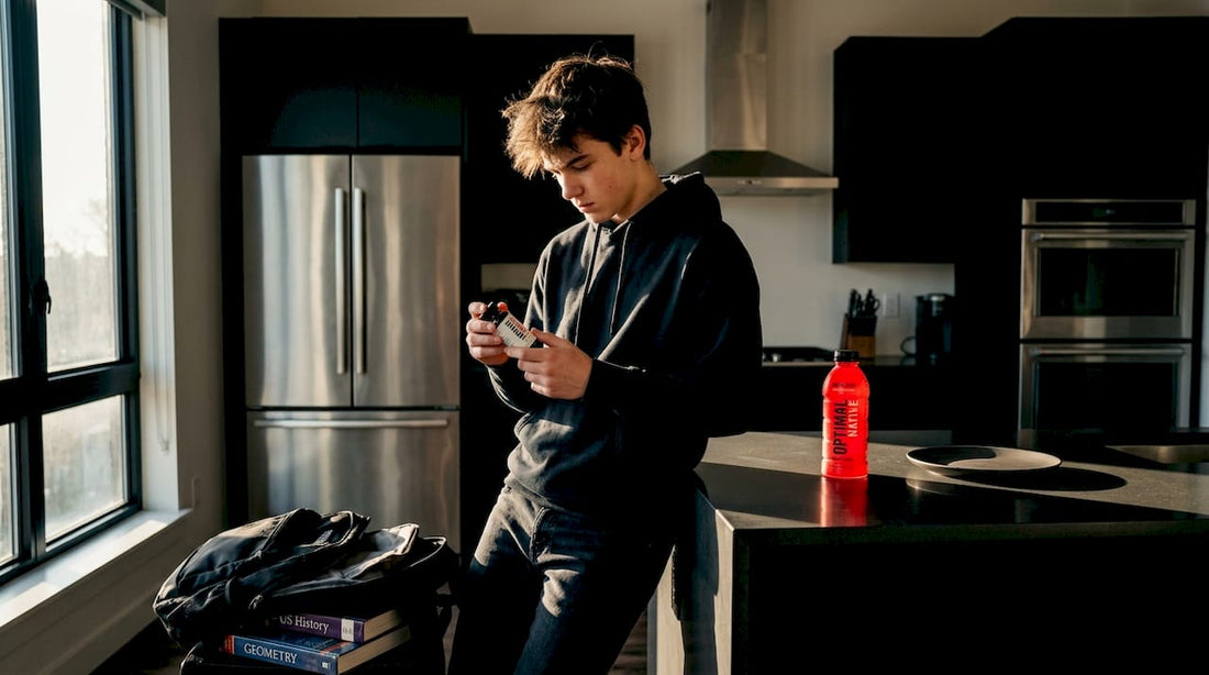 Teen reading energy supplement label in kitchen