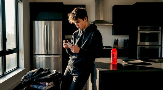 Teen reading energy supplement label in kitchen